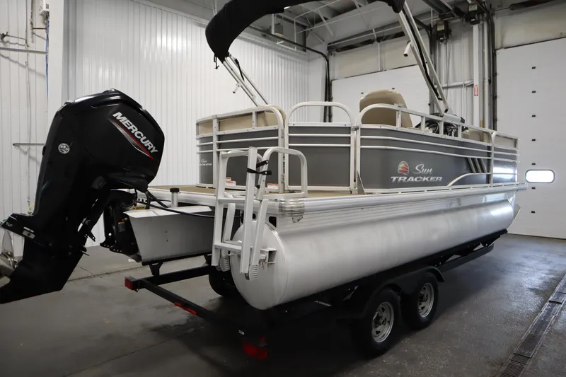 Slide: The Image of 2022 Tracker 20 Party Barge DLX pontoon boat with Mercury outboard motor in a garage. - 5