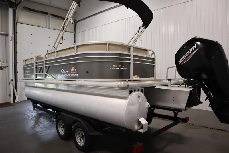 Slide: The Image of 2022 Tracker 20 Party Barge DLX pontoon boat with Mercury outboard motor in a garage. - 7