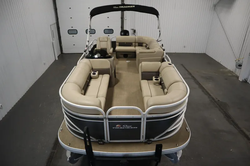 Slide: The Image of 2022 Tracker 20 Party Barge DLX pontoon boat with spacious seating in a garage. - 9