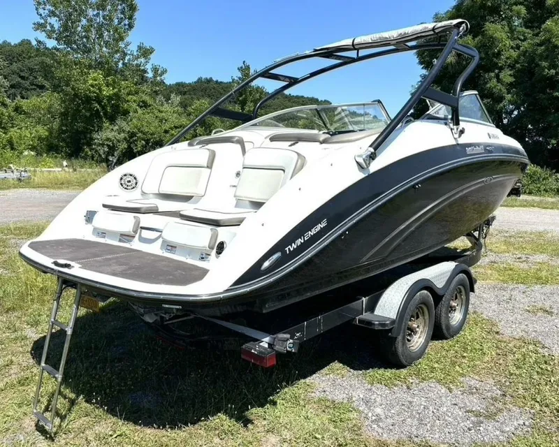 Slide: The Image of 2013 Yamaha Boats 242 Limited S on trailer, parked outdoors, showcasing sleek design and twin engines. - 5