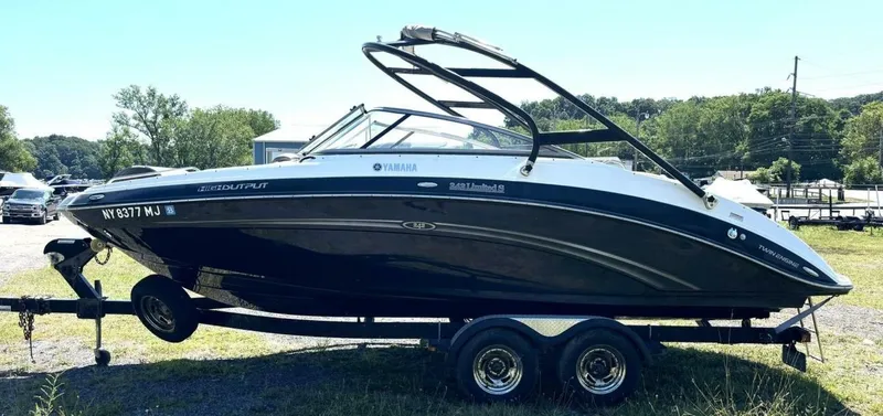 Slide: The Image of 2013 Yamaha Boats 242 Limited S on trailer, black and white design, parked outdoors. - 2