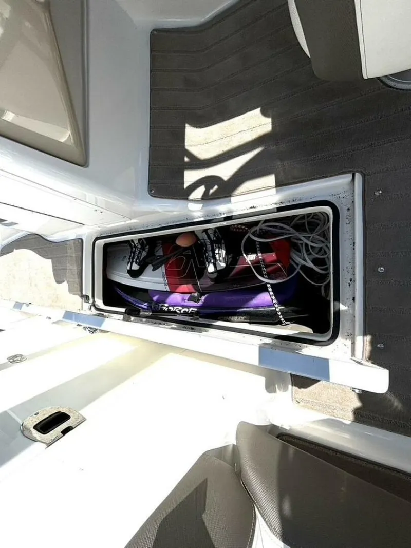 Slide: The Image of Storage compartment on a 2013 Yamaha Boats 242 Limited S, containing a wakeboard and ropes. - 31