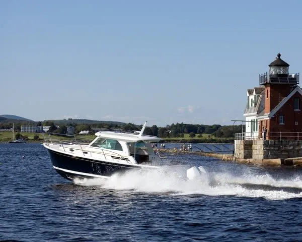 The Image of 2026 Back Cove 34O boat cruising near a lighthouse on a sunny day. - 1