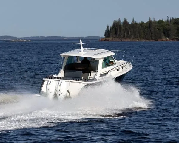 Slide: The Image of 2026 Back Cove 34O cruising on open water near a forested shoreline. - 3