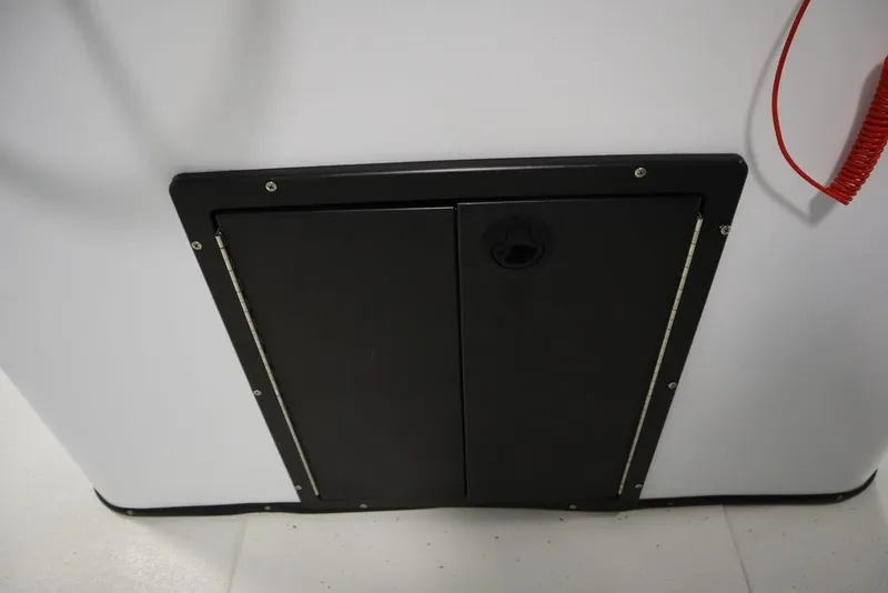 Slide: The Image of 2020 Sun Tracker Party Barge 20 DLX storage compartment with black door and red cord. - 29