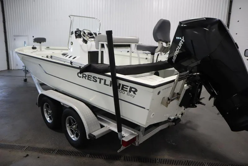 Slide: The Image of A Crestliner 2000 Bay boat with Mercury engine on a dual-axle trailer in a garage. - 8