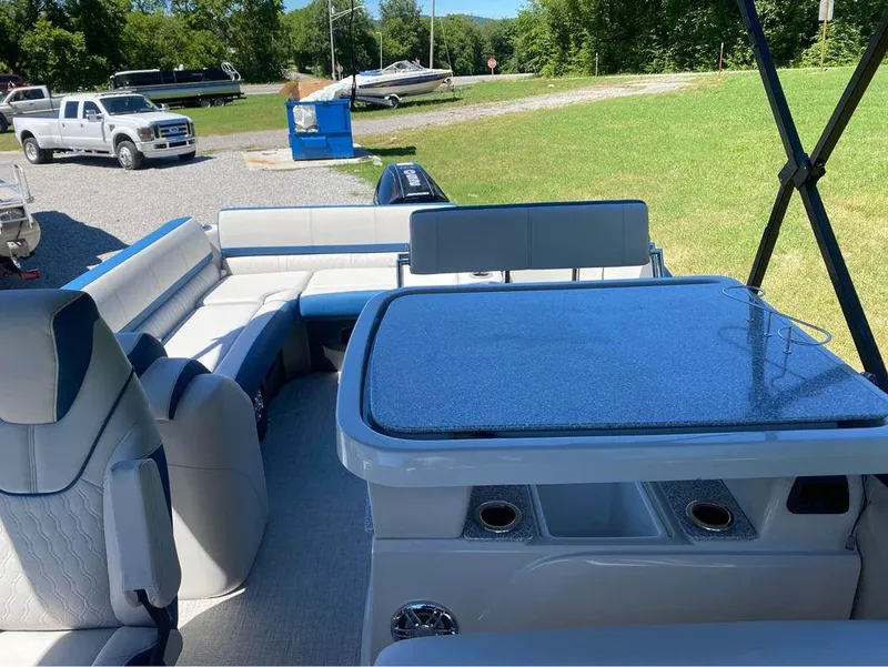 Slide: The Image of 2024 Avalon Catalina Entertainer boat interior with seating and table, parked outdoors. - 6