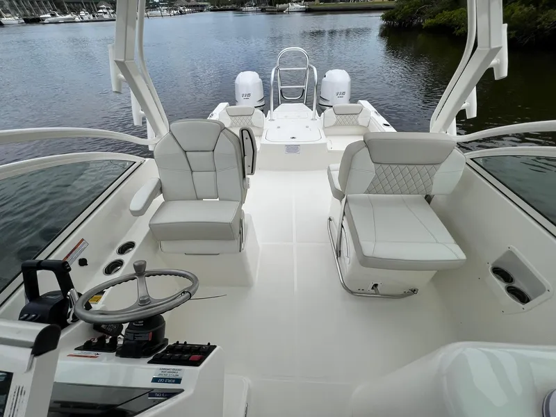 Slide: The Image of 2025 World Cat 230 DC boat interior with white seating and steering wheel on calm water. - 12
