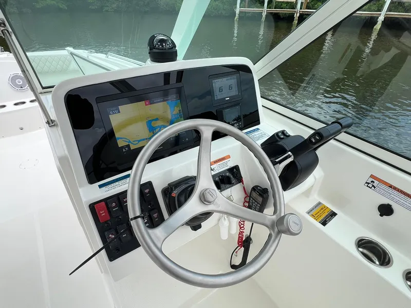 Slide: The Image of 2025 World Cat 230 DC boat dashboard with steering wheel and navigation display. - 15