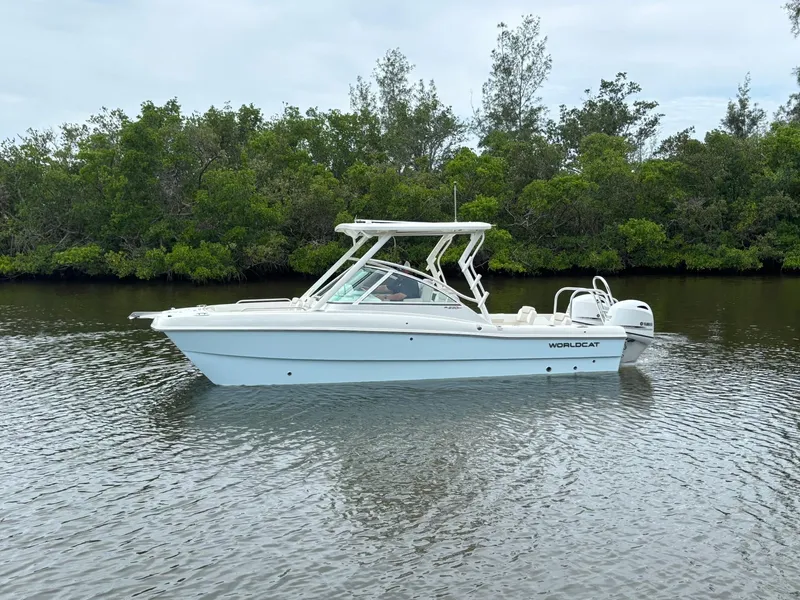 Slide: The Image of 2025 World Cat 230 DC boat on calm water, surrounded by lush greenery. - 5