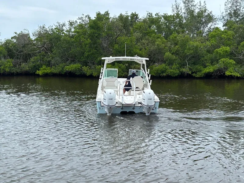 Slide: The Image of 2025 World Cat 230 DC boat cruising on a calm river near lush greenery. - 7