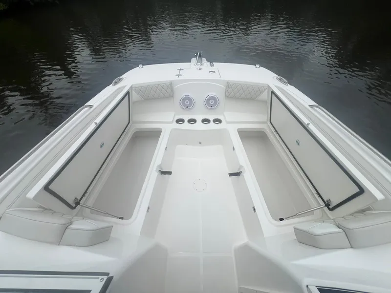 Slide: The Image of 2025 World Cat 230 DC boat interior with open storage compartments on calm water. - 9