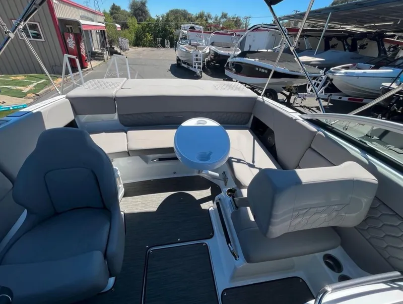 Slide: The Image of 2023 Four Winns H1 boat interior with seating and table, docked among other boats. - 13