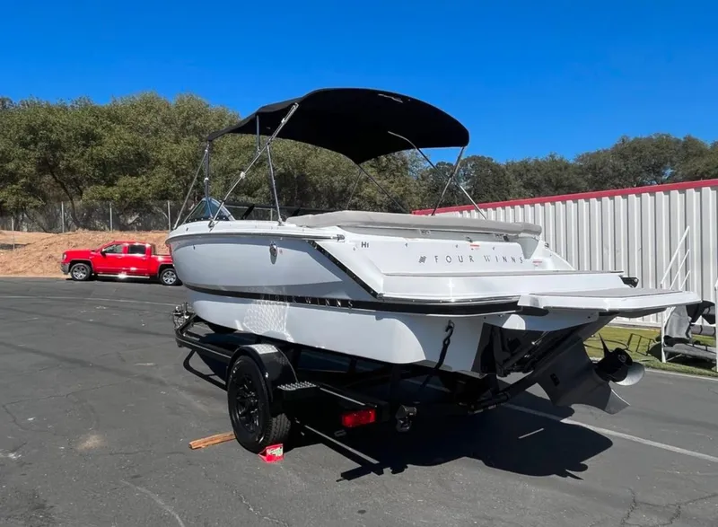 Slide: The Image of 2023 Four Winns H1 boat on trailer, parked outdoors under clear blue sky. - 25