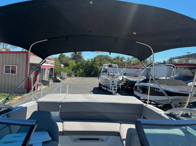 Slide: The Image of 2023 Four Winns H1 boat with canopy, parked in a marina with other boats. - 29