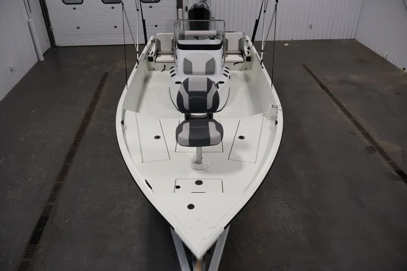 Slide: The Image of 2022 Crestliner 2200 Bay boat interior with seating and fishing rod holders in a garage. - 10