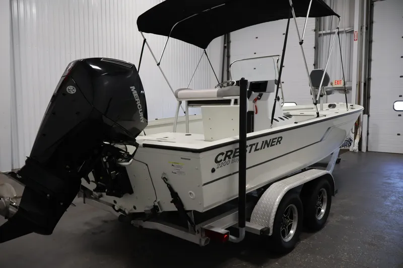 Slide: The Image of 2022 Crestliner 2200 Bay boat with Mercury outboard motor in a garage setting. - 6
