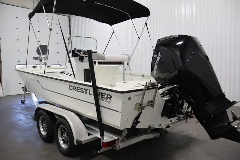 Slide: The Image of 2022 Crestliner 2200 Bay boat with Mercury outboard motor in a garage setting. - 8