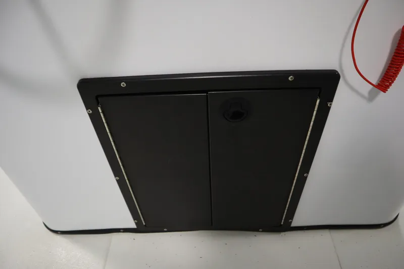 Slide: The Image of 2022 Crestliner 2200 CC boat storage compartment with black panel and red cord. - 30