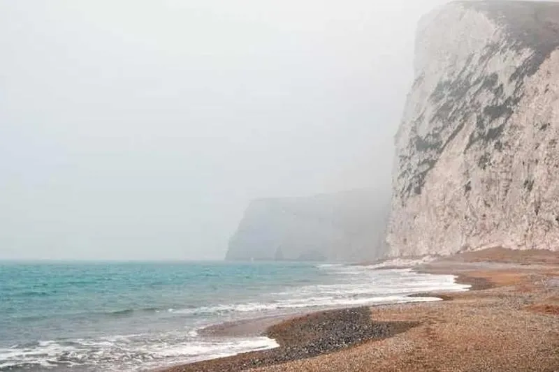 Slide: The Image of Foggy coastal cliffs and pebbled beach with misty sea view, captured by 33rd Strike Group FOX-3637. - 27