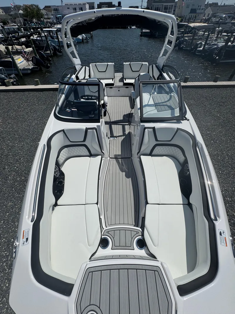 Slide: The Image of 2025 Yamaha Boats 252S with sleek design and spacious seating, docked at a marina. - 11