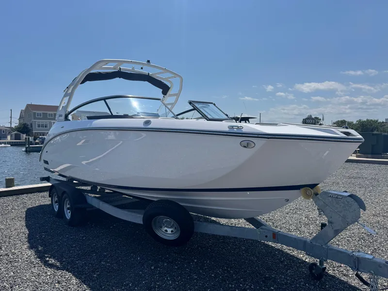 Slide: The Image of 2025 Yamaha Boats 252S on trailer, parked near waterfront under clear sky. - 6