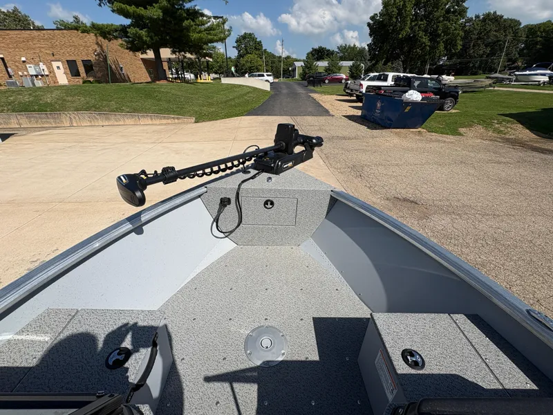 Slide: The Image of 2025 Lund 1875 Alaskan Sport boat interior with trolling motor, parked outdoors. - 12