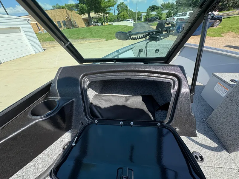 Slide: The Image of 2025 Lund 1875 Alaskan Sport boat interior with open storage compartment and windshield view. - 19