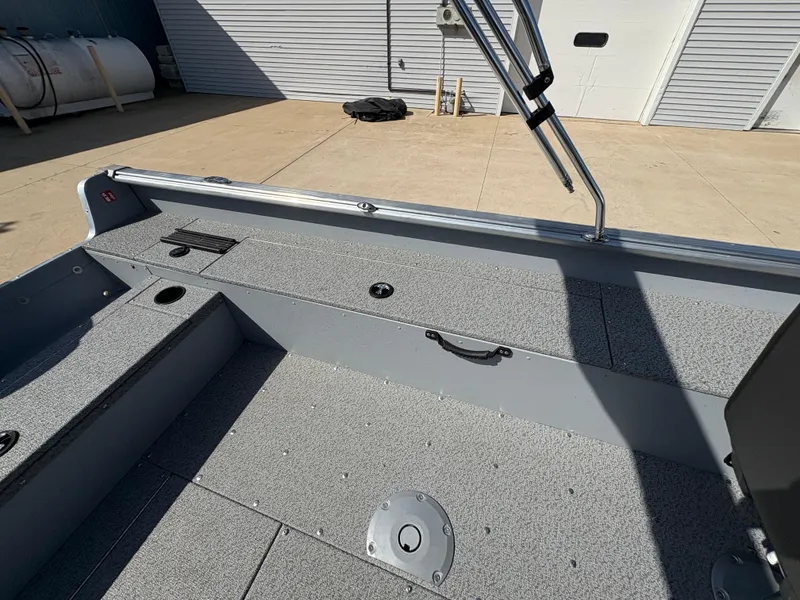 Slide: The Image of 2025 Lund 1875 Alaskan Sport boat interior with gray flooring and storage compartments. - 23