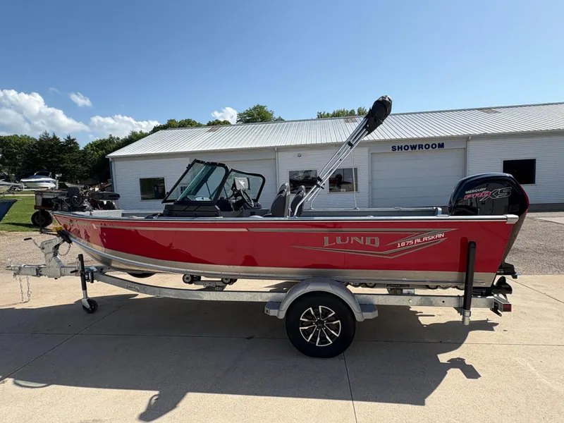 Slide: The Image of 2025 Lund 1875 Alaskan Sport boat in red, parked outside a showroom. - 4