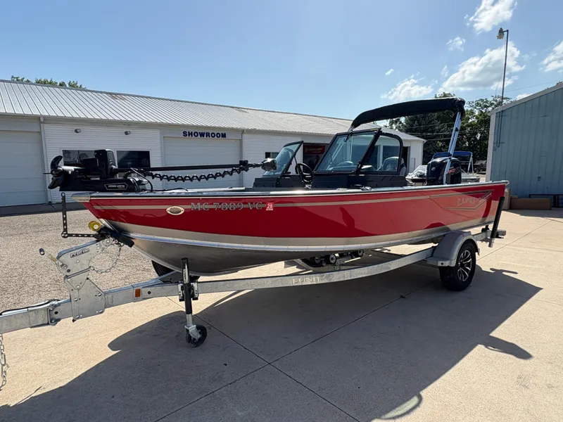 Slide: The Image of 2025 Lund 1875 Alaskan Sport boat in red on a trailer outside a showroom. - 5