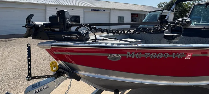 Slide: The Image of 2025 Lund 1875 Alaskan Sport boat with Minn Kota motor, parked outside a showroom. - 7