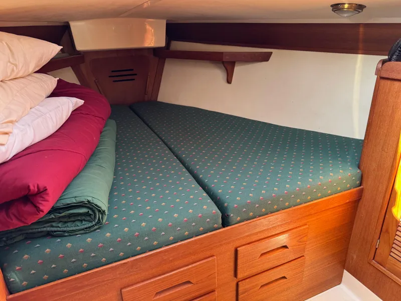 Slide: The Image of Cozy cabin bed in 1997 Tartan 3500 sailboat with green cushions and wooden storage. - 13