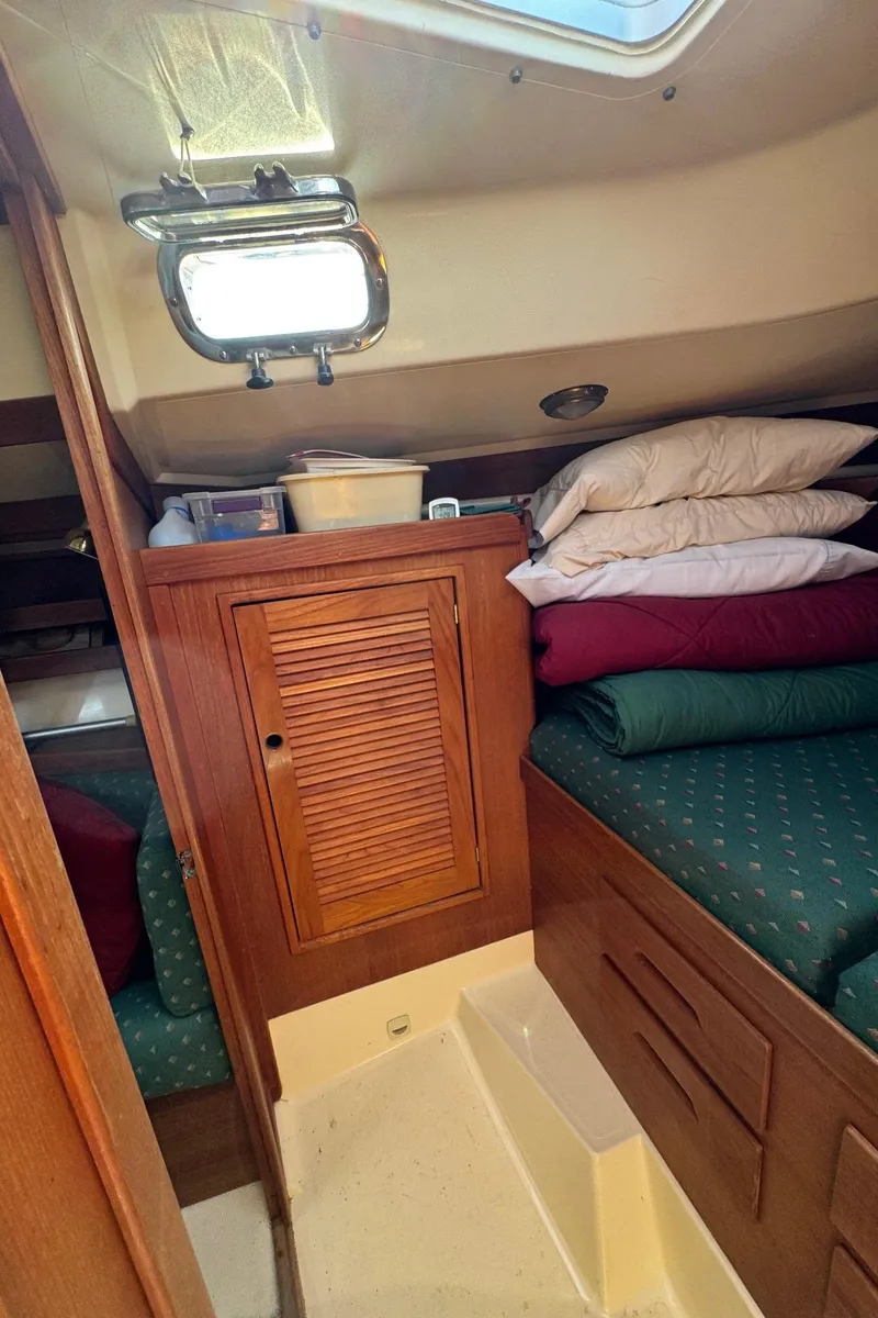 Slide: The Image of Cozy cabin interior of 1997 Tartan 3500 sailboat with wooden cabinetry and bedding. - 14