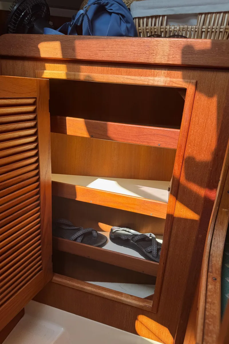 Slide: The Image of Wooden cabinet with open door, showcasing shelves inside a 1997 Tartan 3500 boat. - 15