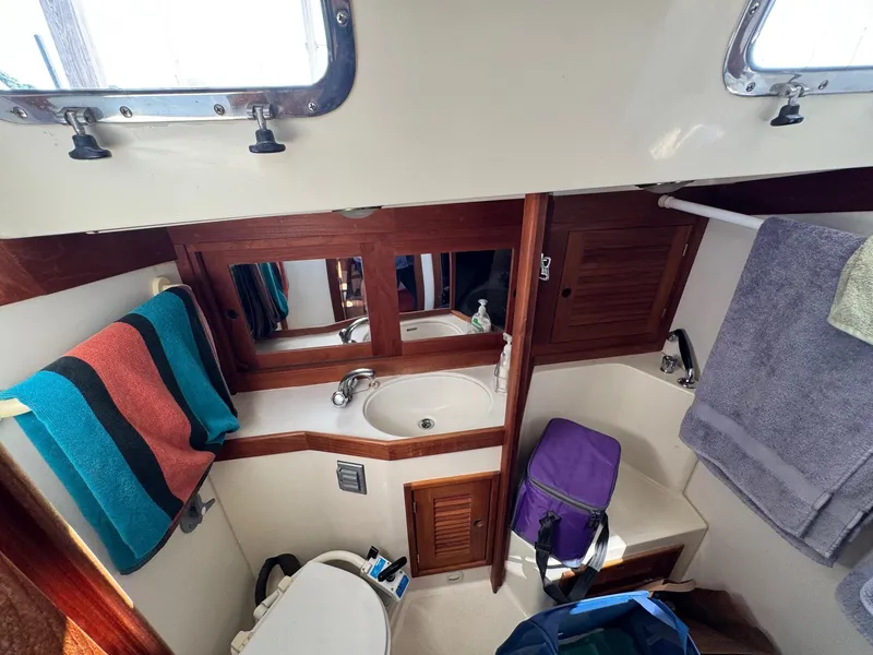 Slide: The Image of 1997 Tartan 3500 yacht bathroom with sink, mirror, and colorful towels. - 21
