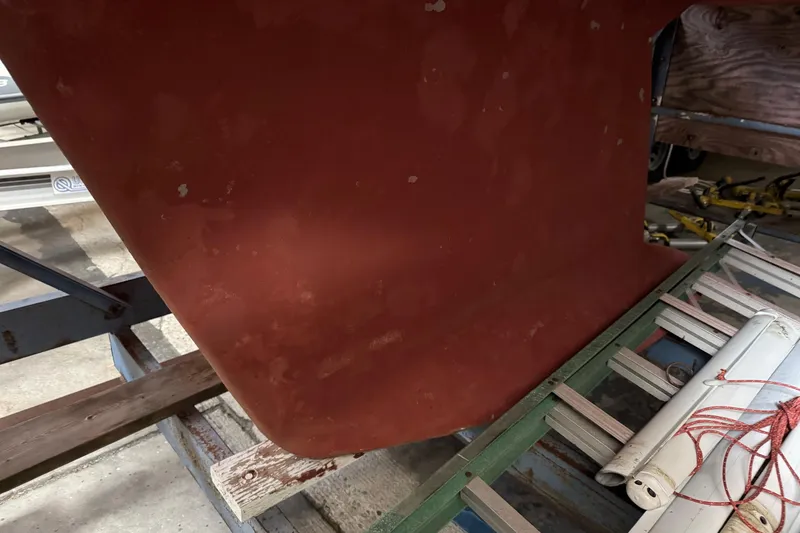 Slide: The Image of Red hull of a 1997 Tartan 3500 sailboat in a workshop setting. - 29