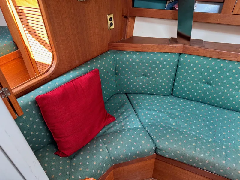 Slide: The Image of Cozy interior of 1997 Tartan 3500 sailboat with green patterned seating and red cushion. - 9