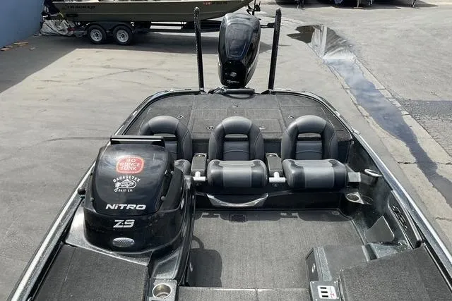 Slide: The Image of 2015 Nitro Z-9 boat interior with three seats and motor, parked on pavement. - 19