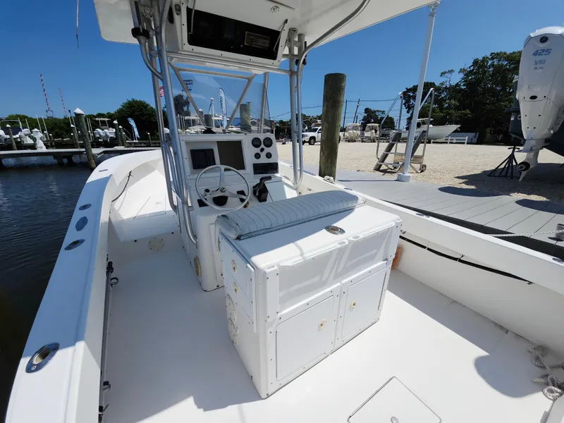 Slide: The Image of 2002 Regulator 23 Classic boat interior with steering console and seating, docked by the water. - 10