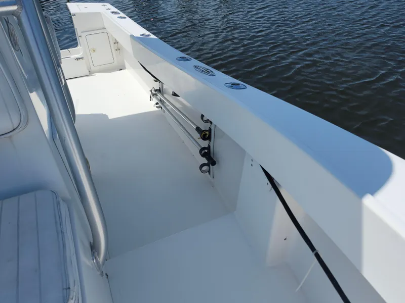 Slide: The Image of 2002 Regulator 23 Classic boat deck with fishing rod holders, on calm water. - 19