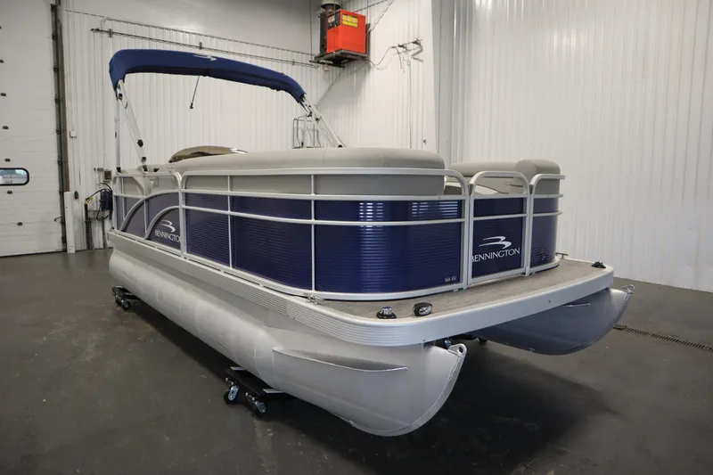 Slide: The Image of 2020 Bennington 16 SL pontoon boat in a garage, featuring a blue and silver design. - 3