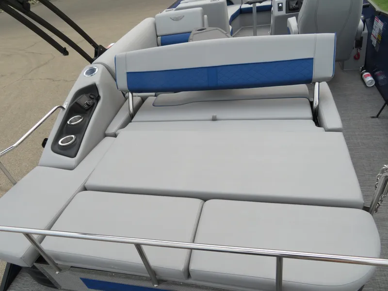 Slide: The Image of 2024 Bennington 25 LTSB boat interior with gray and blue seating, cup holders, and railing. - 14