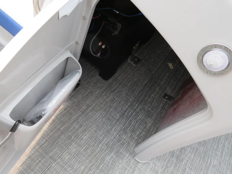 Slide: The Image of 2024 Bennington 25 LTSB interior storage compartment with carpeted flooring and LED light. - 18