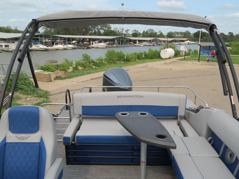 Slide: The Image of 2024 Bennington 25 LTSB pontoon boat with blue and gray seating, docked by a marina. - 19