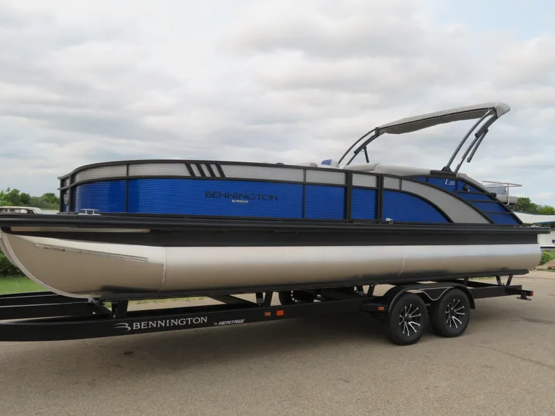 Slide: The Image of 2024 Bennington 25 LTSB pontoon boat on trailer, featuring sleek blue and silver design. - 23