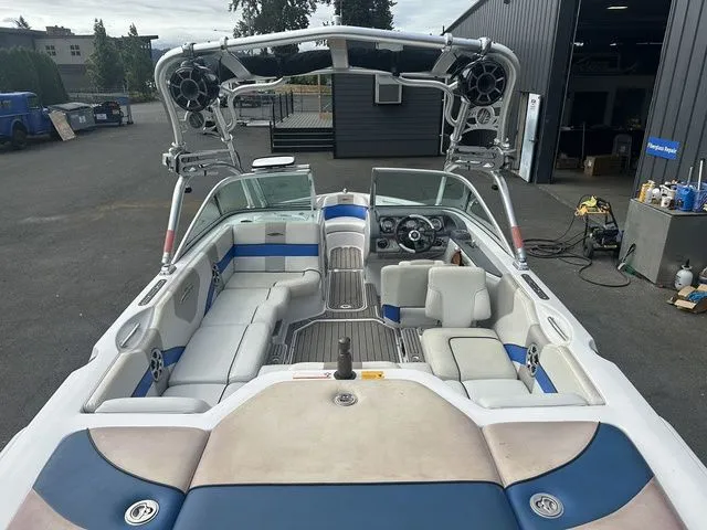 Slide: The Image of 2007 Nautique Super Air Nautique 210 boat interior with seating and speakers in a garage setting. - 7