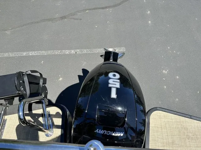 Slide: The Image of 2025 Harris Cruiser 210 CWDH with Mercury 150 outboard motor, parked on pavement. - 10