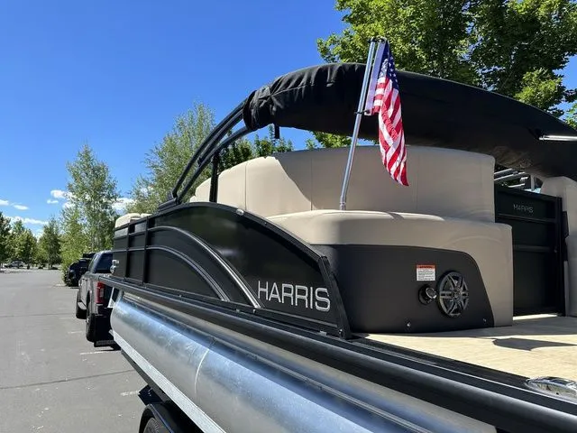 Slide: The Image of 2025 Harris Cruiser 210 CWDH pontoon boat with American flag, parked outdoors. - 12