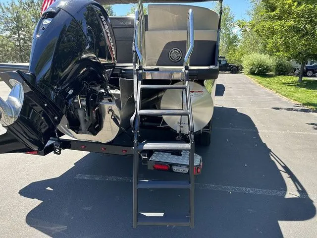 Slide: The Image of 2025 Harris Cruiser 210 CWDH boat with ladder and Mercury engine, parked outdoors. - 9